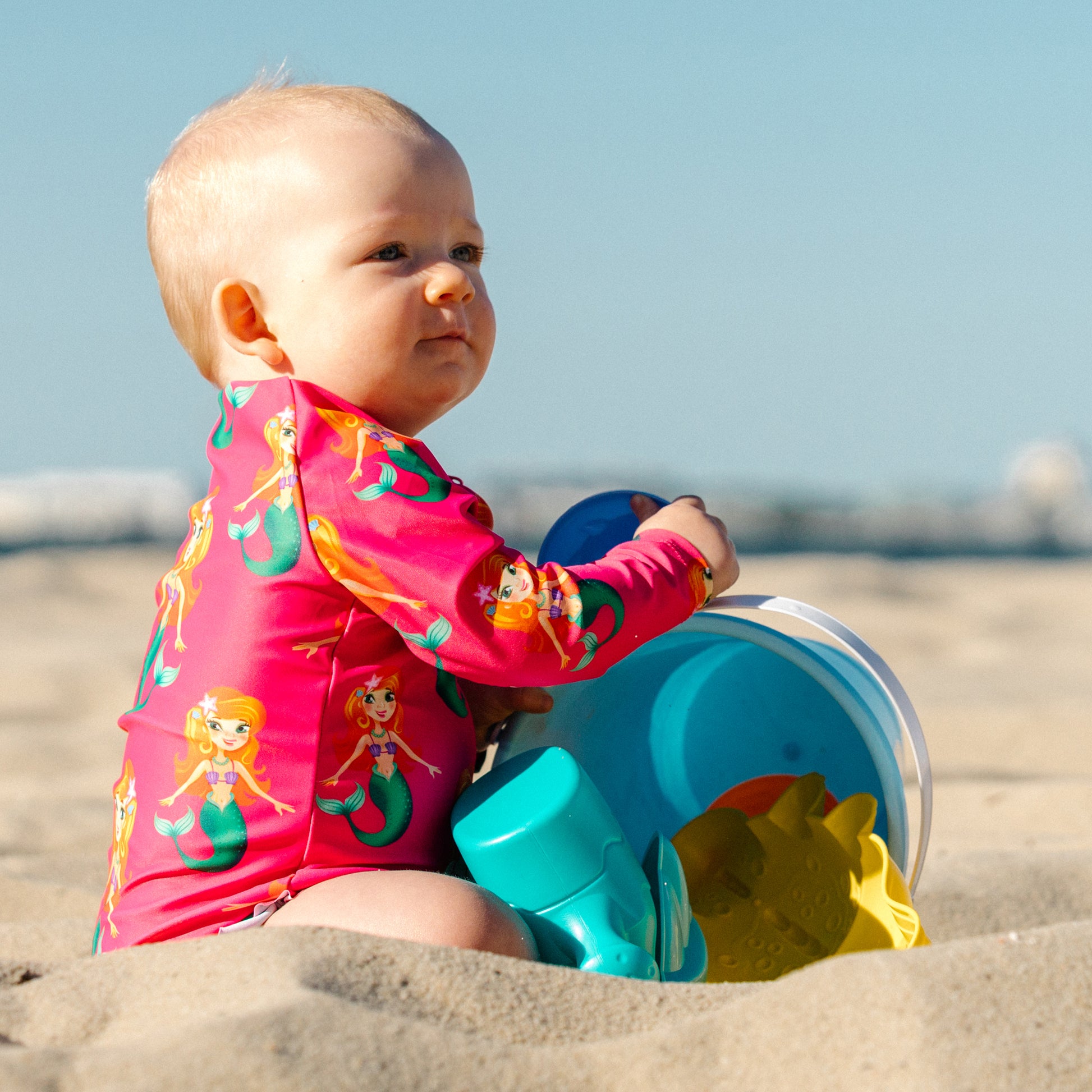 Splashy Tots Pink baby girl swimwear - Girls one piece mermaid pattern swimsuit - Side view at beach